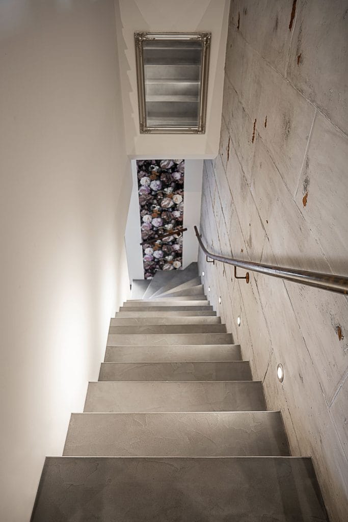 Betontreppenaufgang mit Geländer an der Wand und Beleuchtung